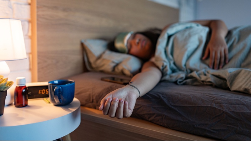 Donna dorme a letto con medicine sul comodino